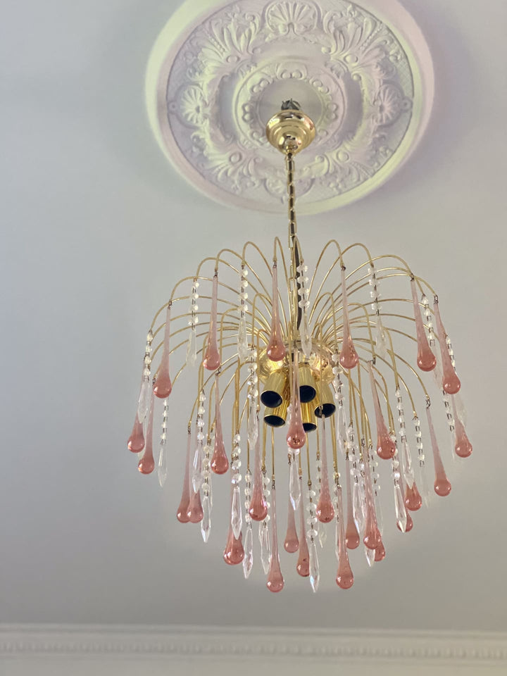 Decorative chandelier with pink and clear crystals on a ceiling with intricate design.